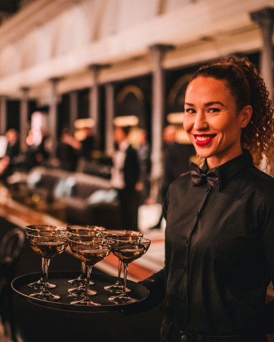 Messehostess mit einem Tablett, darauf Getränke