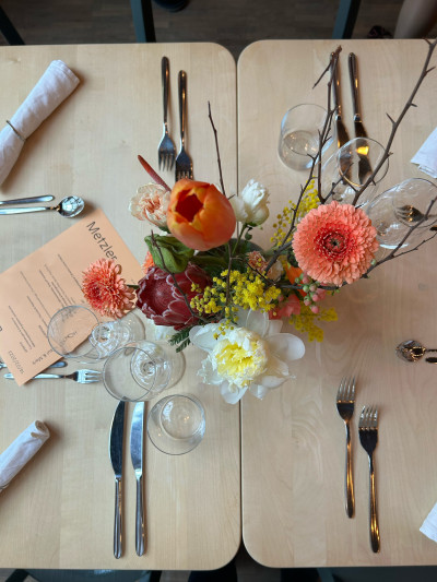 Blick von oben auf einen gedeckten und dekorierten Tisch im Emma Metzler, im Zentrum ist eine sommerliche Blumendekoration