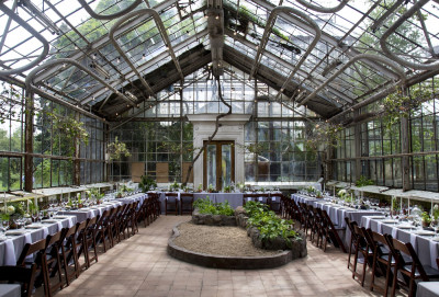 Großes lichtdurchflutetes Glashaus mit langen Dinnertafeln
