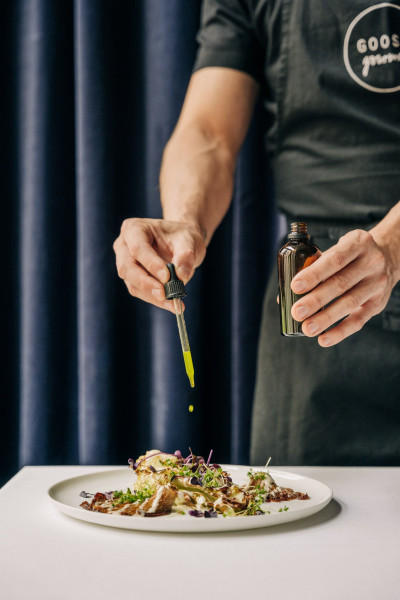 Catering Frankfurt auf weißem Teller wird von einem Mitarbeiter von GOOSE Gourmet Catering vorbereitet.