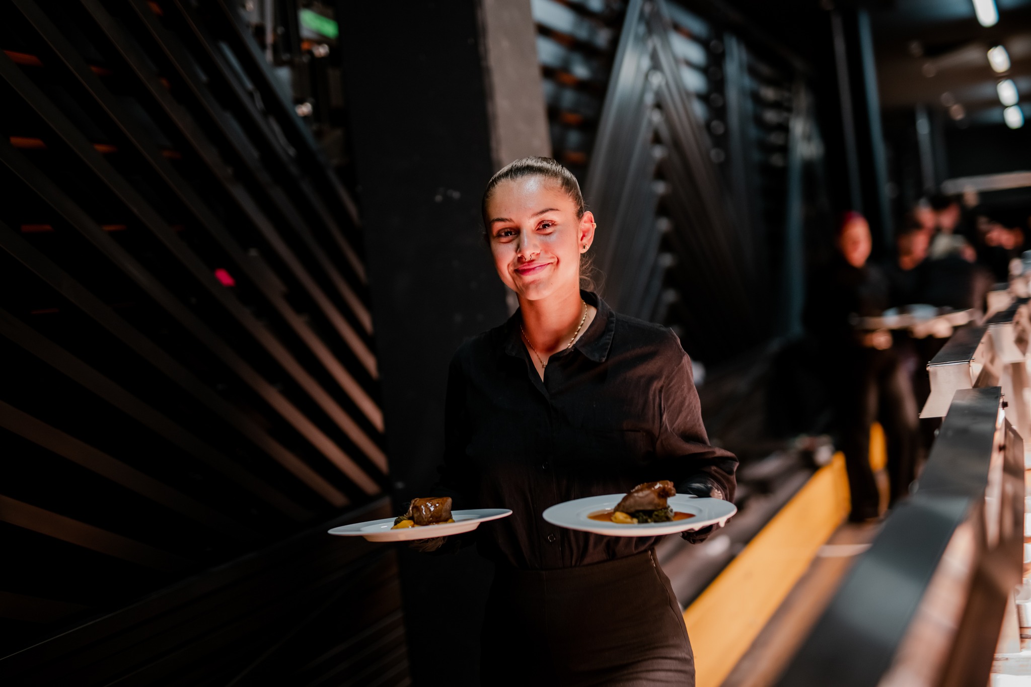 Freundliche Servicekraft mit zwei Tellern in den Händen