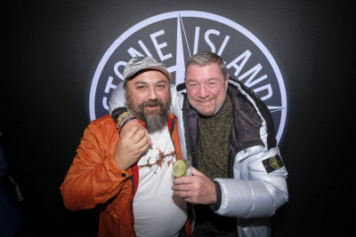 Zwei Personen vor dem Stone Island Logo