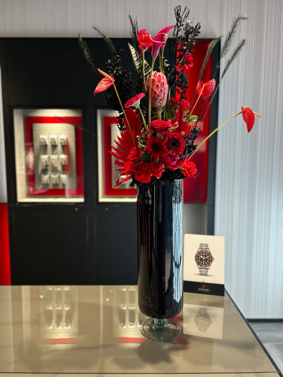 Rotes Blumengesteck in schwarzer Vase, passend zum Tudor Branding